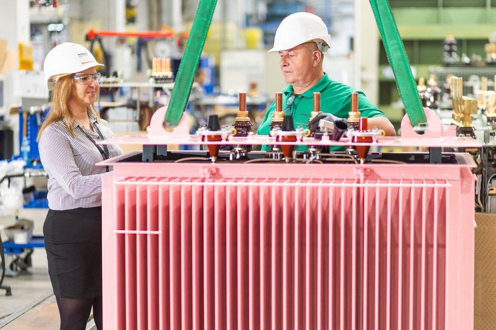 Zdjęcie przedstawia panią inżynier i mechanika stojących przy różowym transformatorze zaprojektowanym w celu wsparcia łódzkiego stowarzyszenia pomagającego walczyć z rakiem piersi.