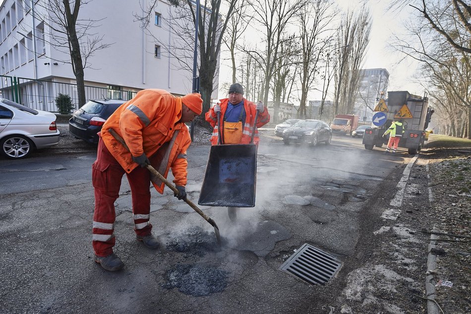 mężczyźni pracują przy łataniu drogi