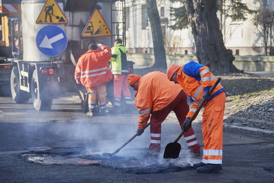 mężczyźni pracują przy łataniu drogi