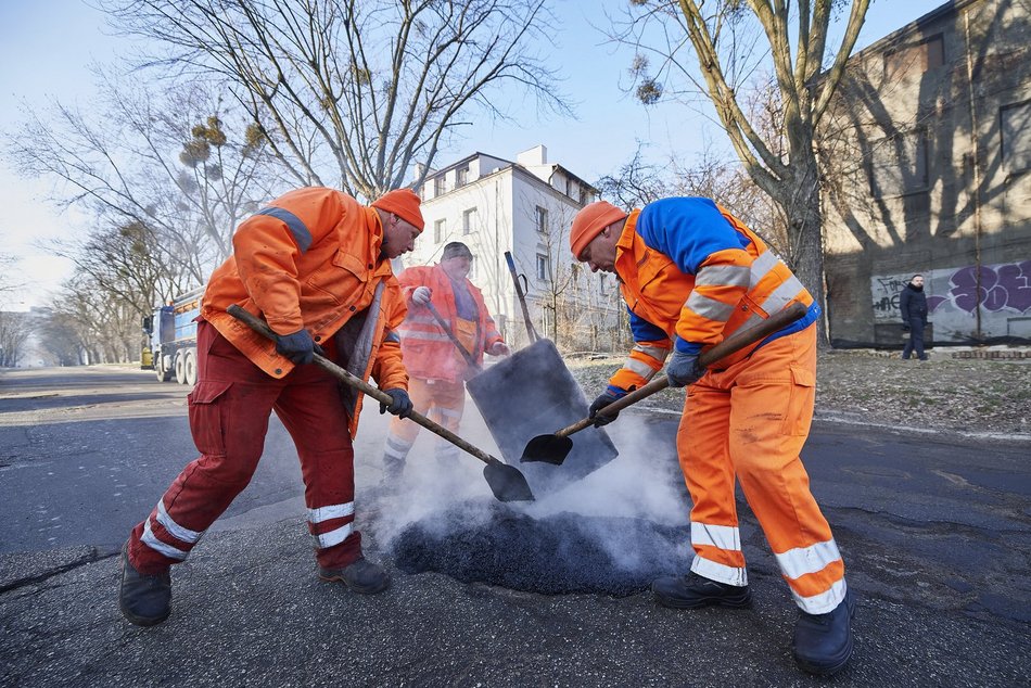 mężczyźni pracują przy łataniu drogi