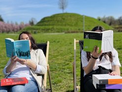 dwie osoby zasłaniające się książkami