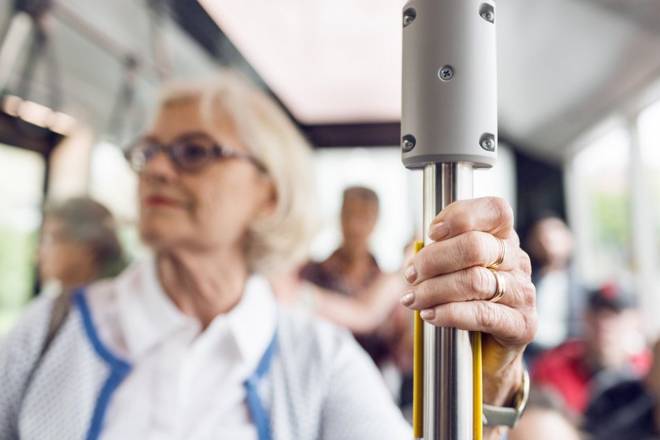 Starsza kobieta stojąca w autobusie 